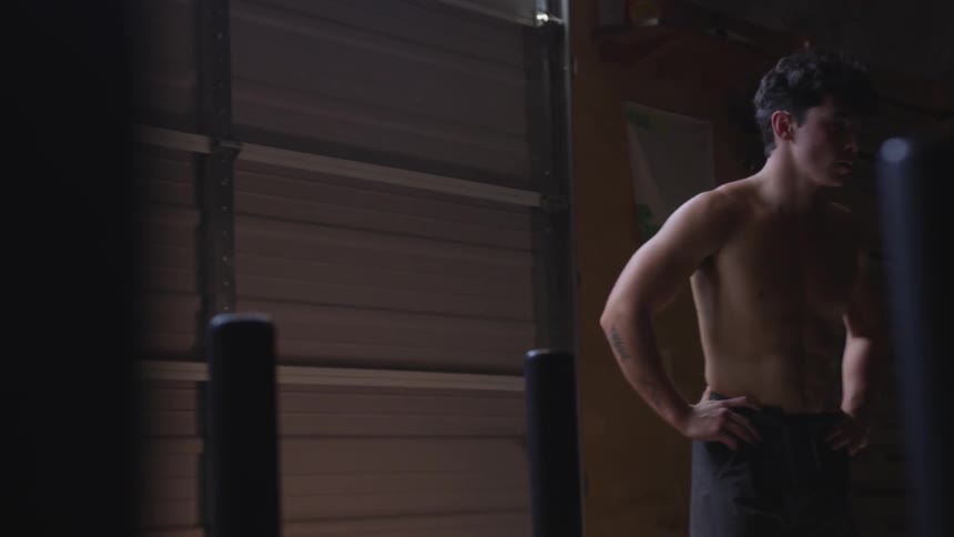 A man is standing shirtless in the gym