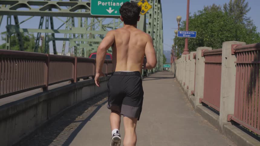 Man runs on sidewalk along bridge