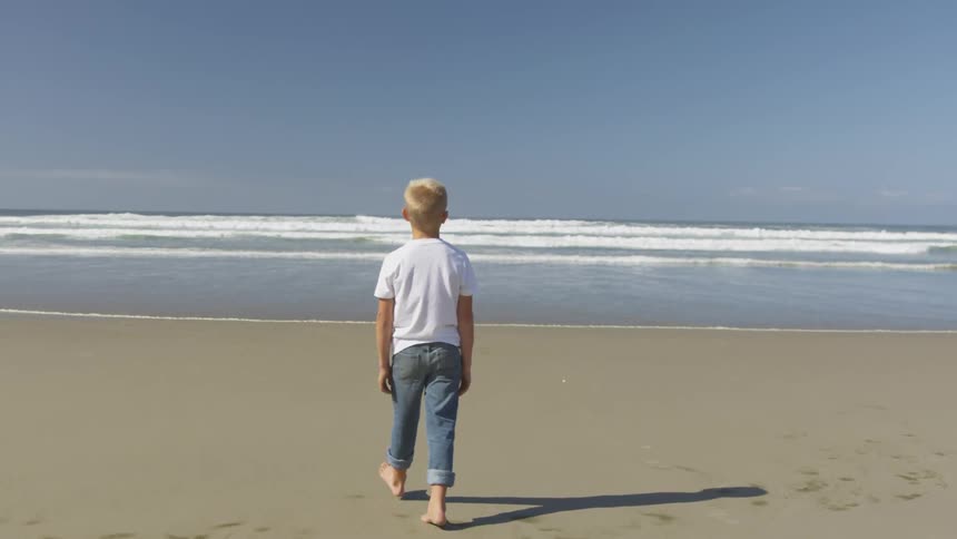 A child walks towards the waves on a beach