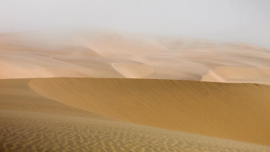 The winds blows over the sand dunes in a desert