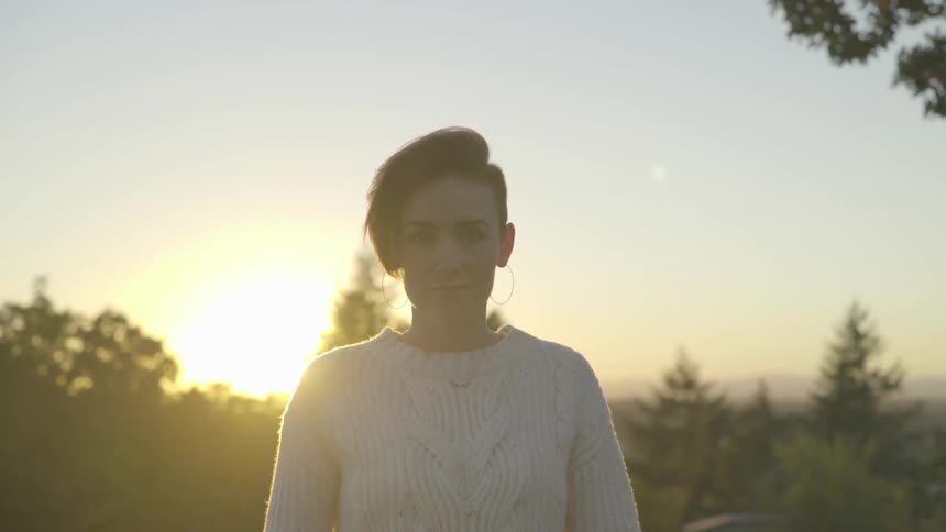 A woman stands outside during sunrise