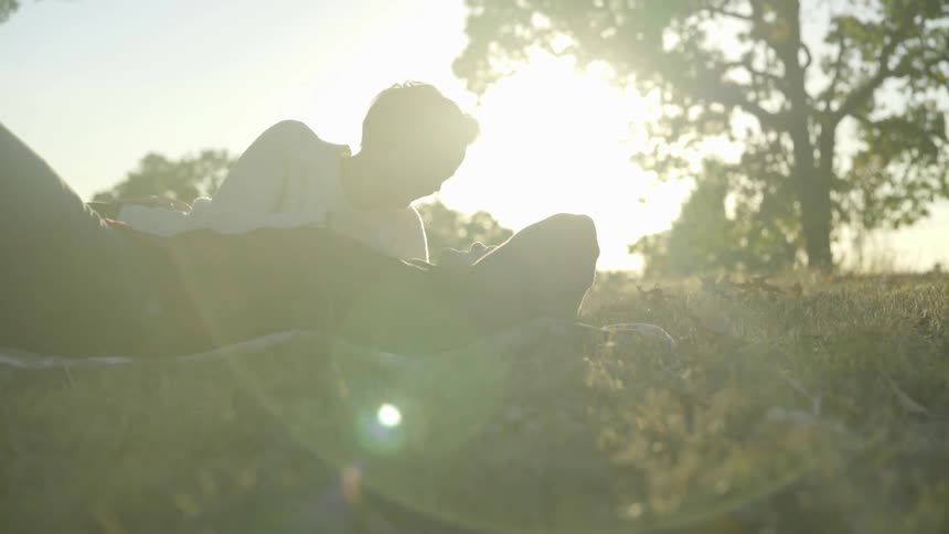 A woman and a man laying in the grass talking