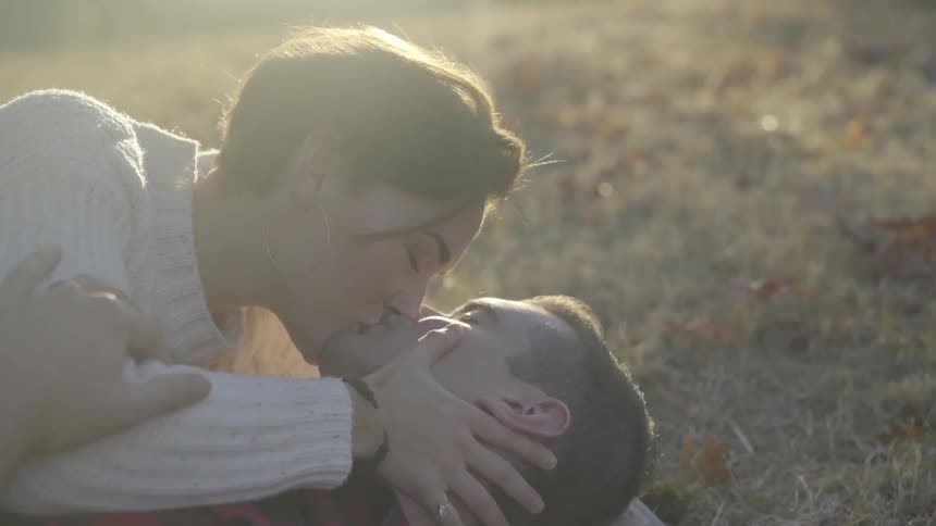 A man and a woman kissing in a field