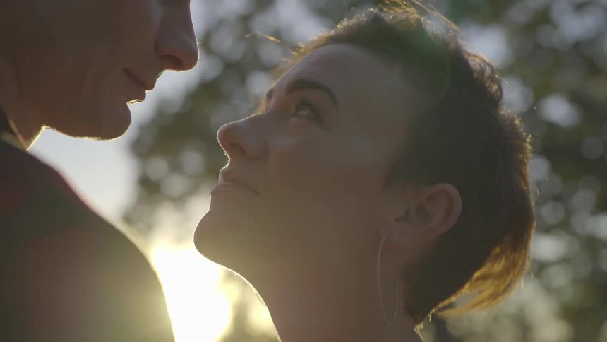 A woman stands looking lovingly up at a man as he embraces her closely