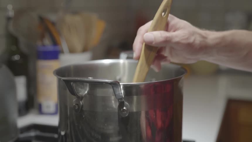 A man stirring a pot with a wooden utensil