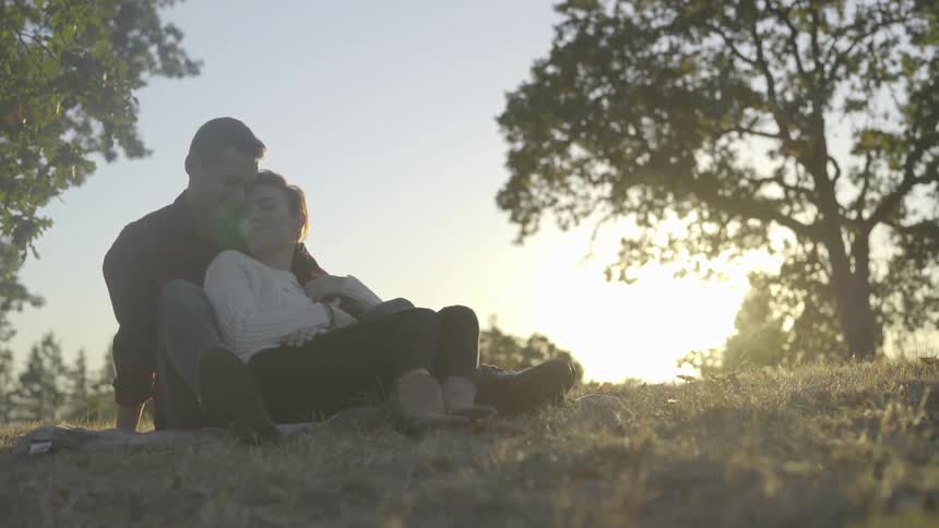 Man and woman cuddle sitting outdoors