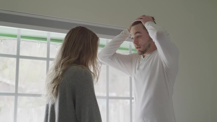 Man and blonde woman argue in room during daylight