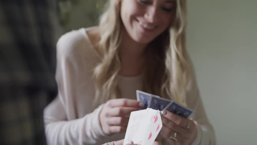 Two people hold playing cards looking at each other and smiling