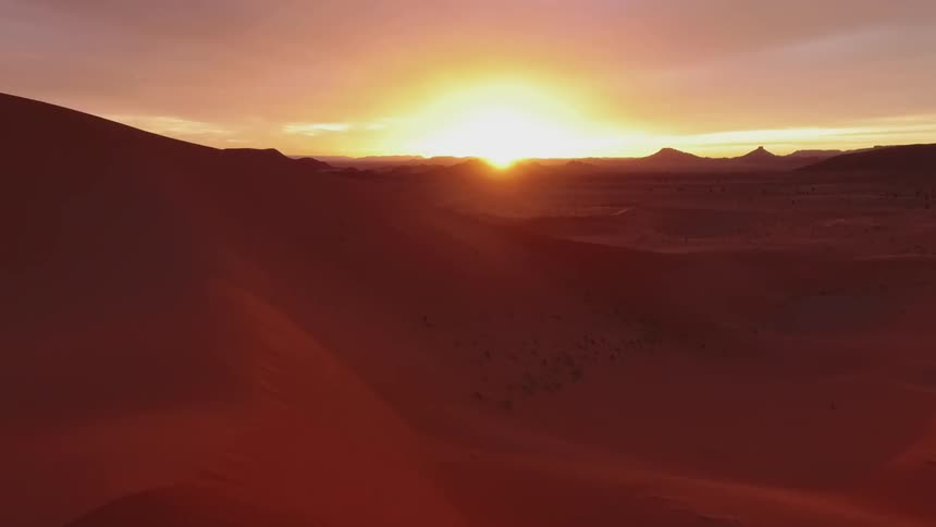 A vast desert landscape against a red glowing sun