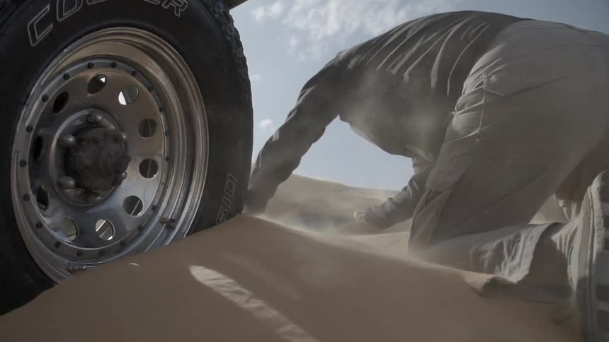 Man tries to dig vehicle out of sand dune