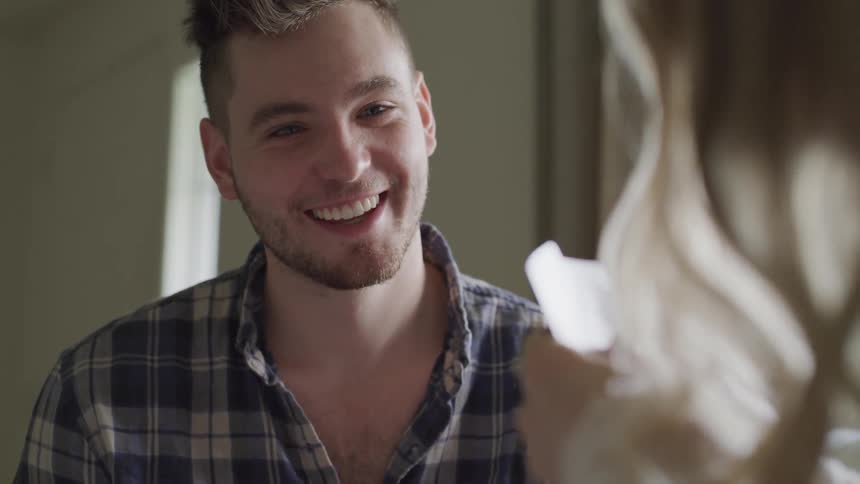 A man smiles and laughs at a woman that is holding playing cards