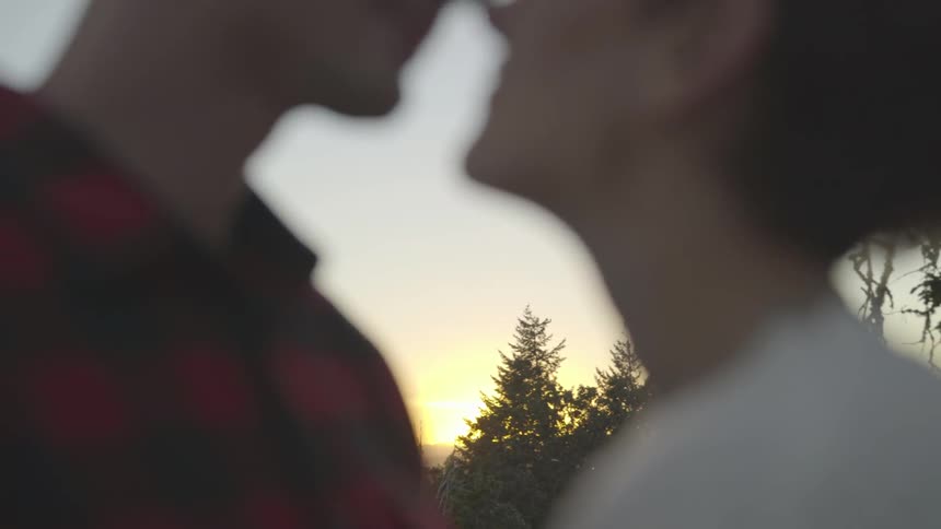 Couple face each other and kiss at sunset