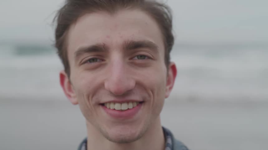 A man smiles broadly on a beach