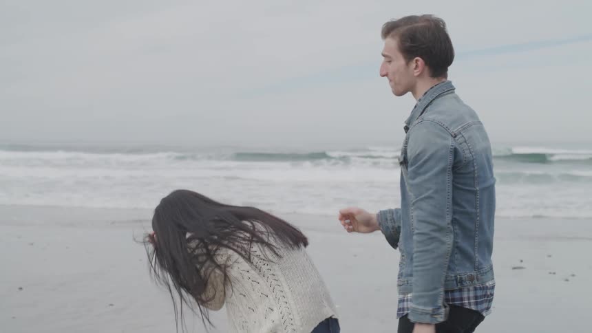 A man tries to comfort a woman sobbing on a beach