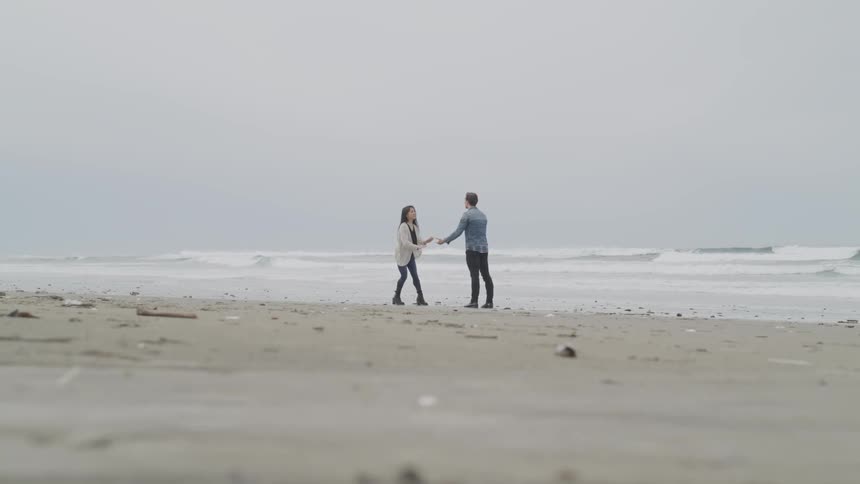 A man and woman argue on a sandy beach
