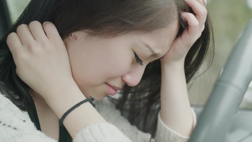 A sad woman rests her head on her hand