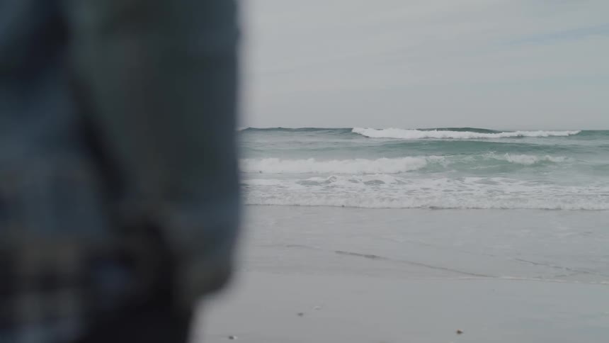 Waves crash upon a beach on a cloudy day