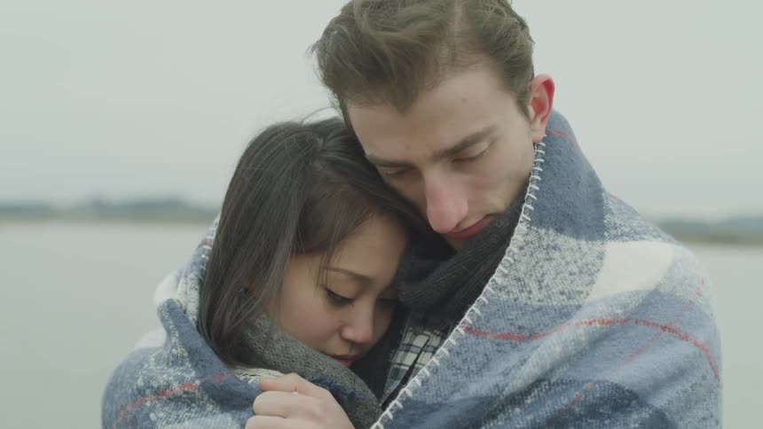 A man hugs a child closely wrapped in a blanket