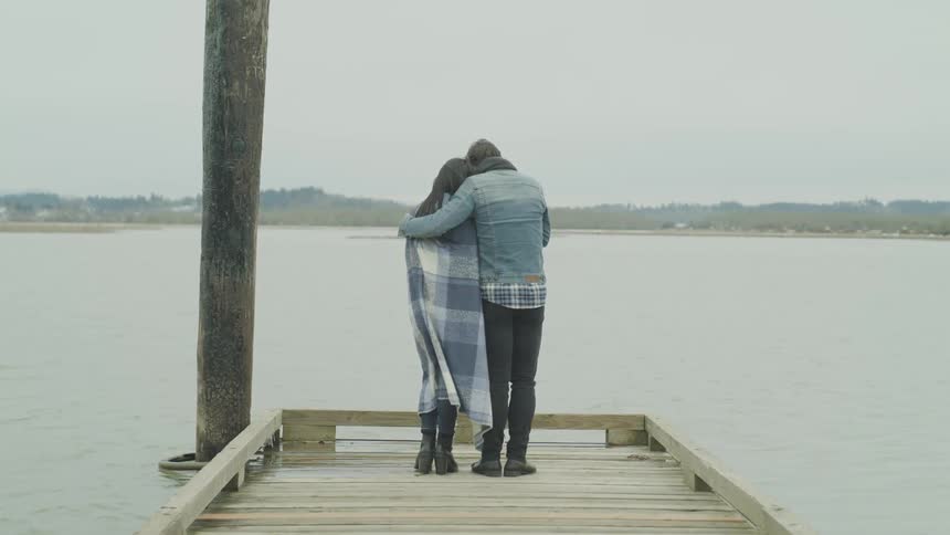A man and woman hugging while standing at the end of a dock