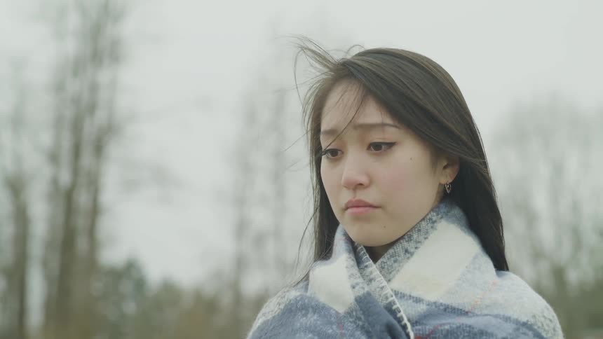 An asian woman looks around outside