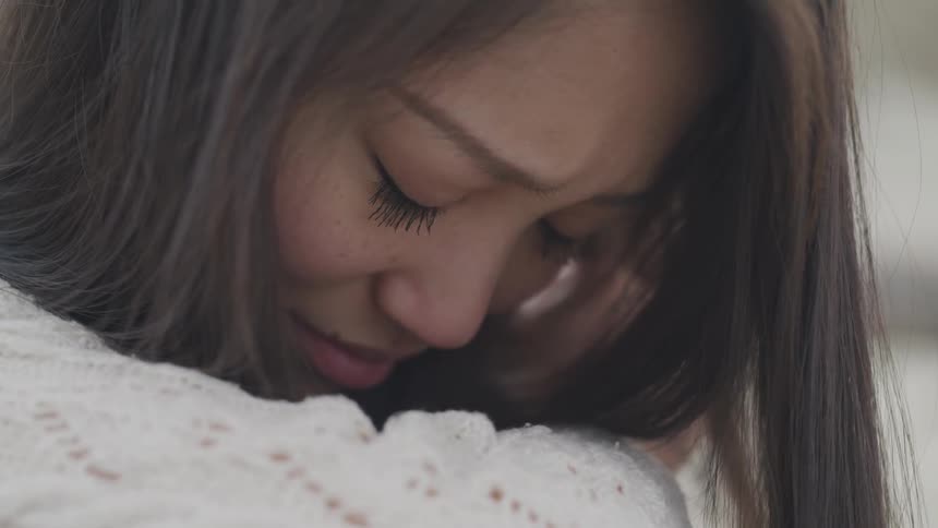 A young asian girl raises and then lowers her head over her arm