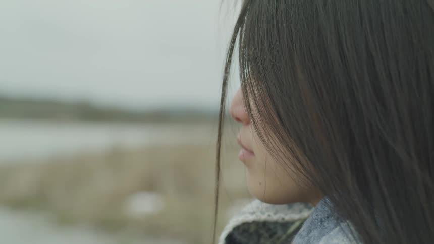 A woman stands outdoors and looks off into the distance