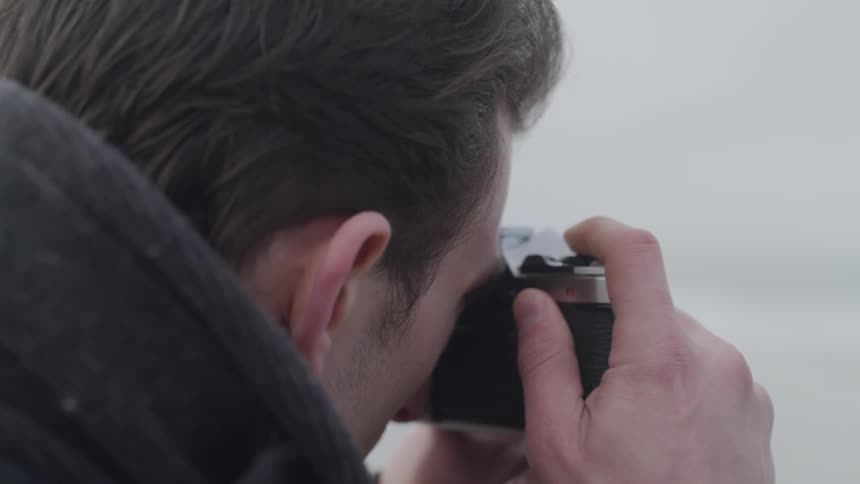A man outside taking a picture with a camera