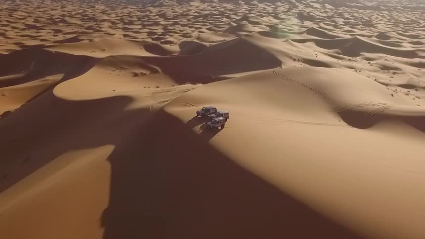 Vehicles parked on a sand dune in the desert