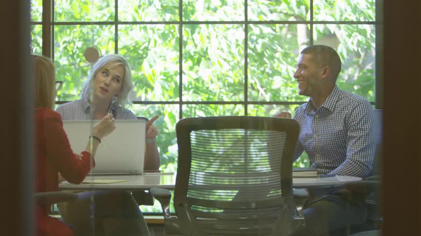 Two women and a man having a discussion in a conference room during the day