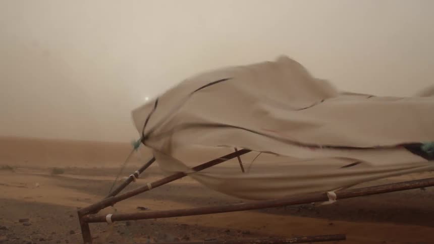 Canvas and wood structure being torn apart by a sandstorm