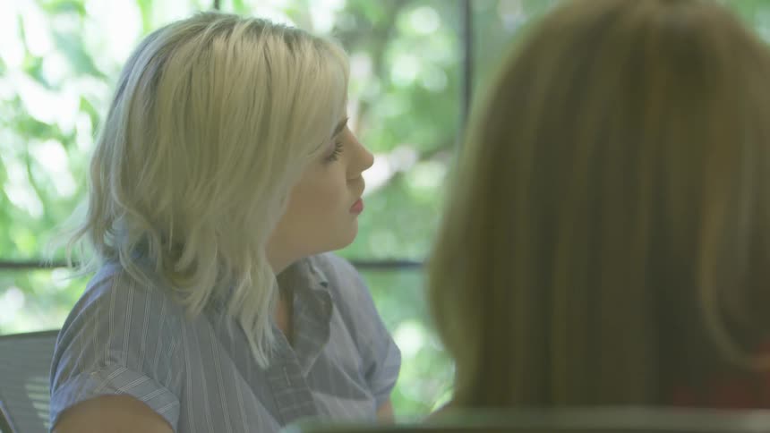 Two women sitting and talking by a window