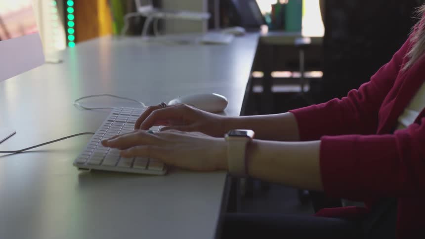 Woman types on computer keyboard at table
