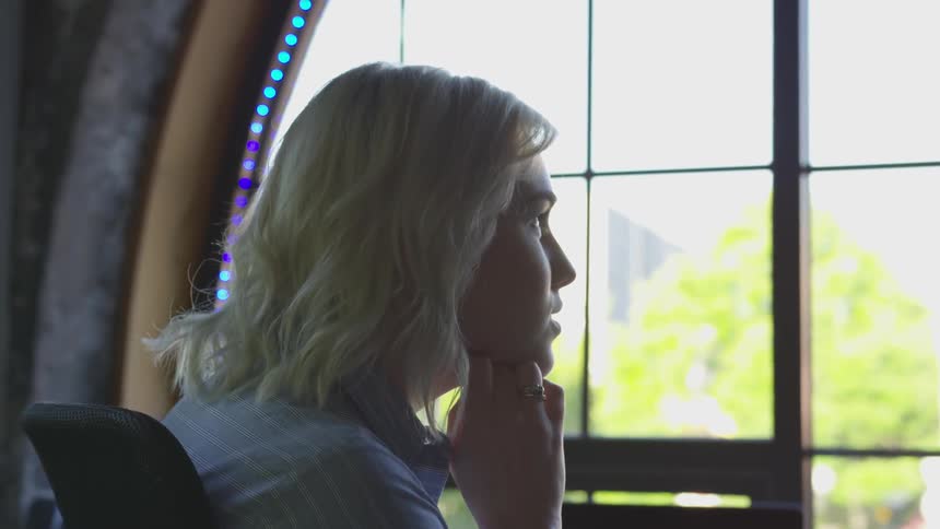 A woman looks out a large window