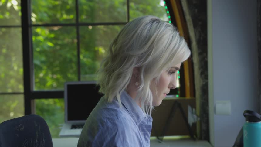 A young woman sits at her desk