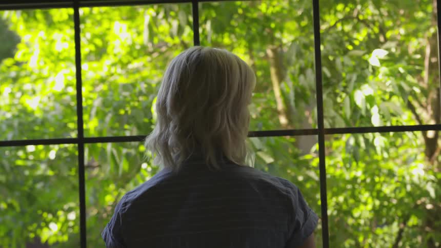A white woman looks out a window