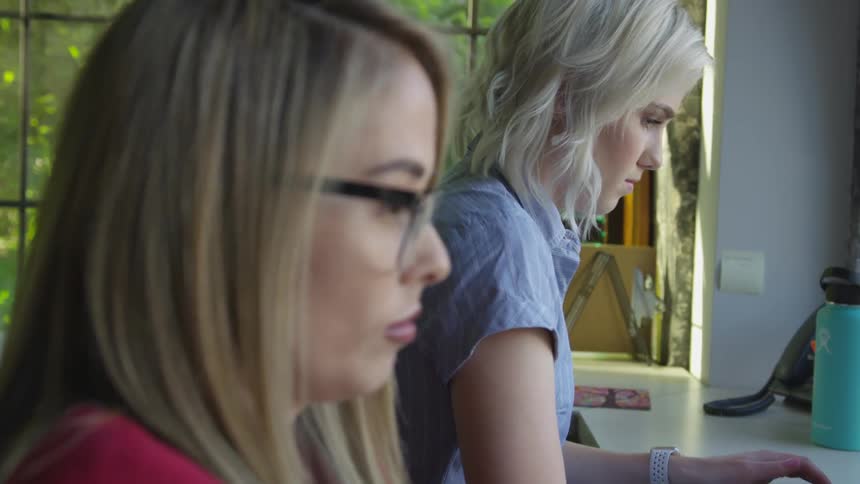 Two women sitting at desk working on computers