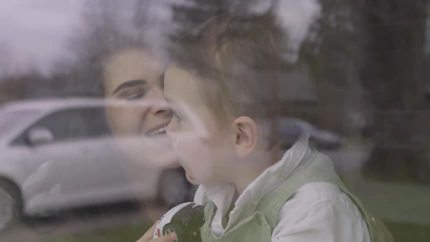 A mother and child are laughing looking out a window