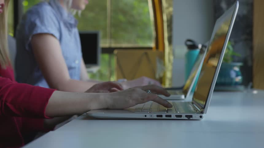 People sitting at table working on laptop computers