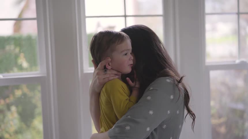 Mother plays with young son while holding him