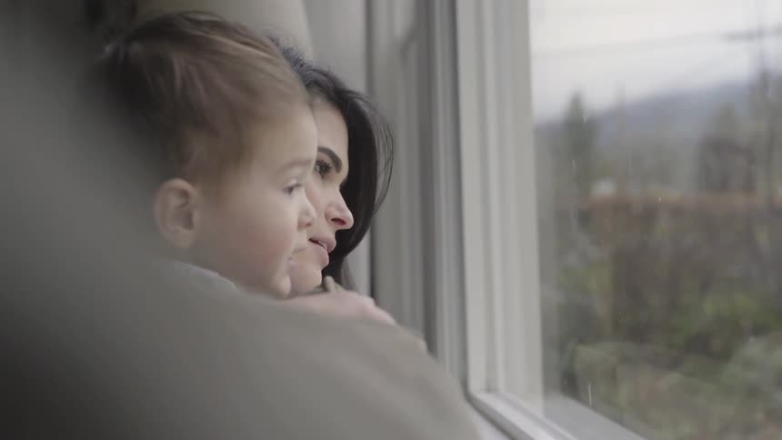 A woman and a baby look out the window