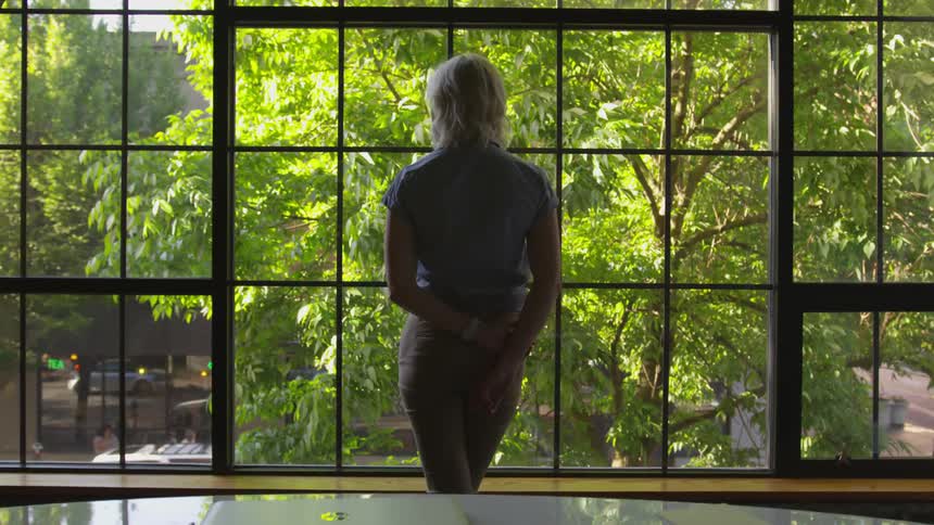 A woman standing in front of a window staring out of it