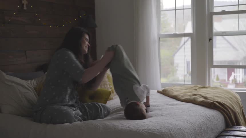 Mom and kids play on the bed in their pajamas