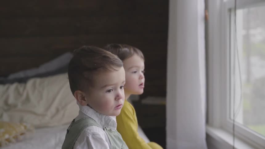 Boys sit on bed looking out the window