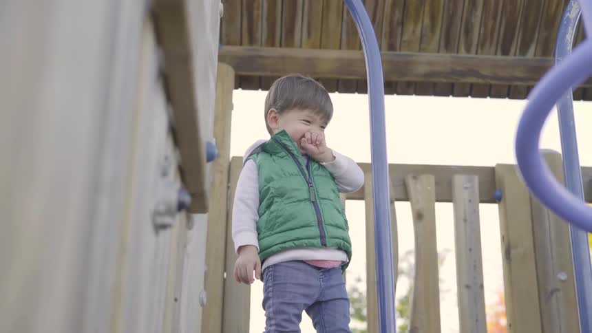 Male toddler stands in an activity center as he smiles
