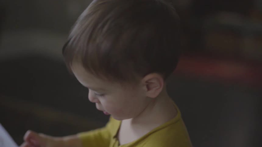 A little boy looks at a book with a young woman