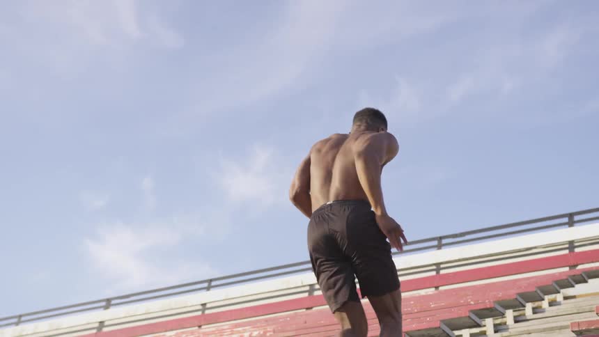 A young athlete runs vigorously up the bleacher steps in a stadium