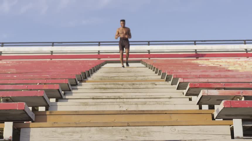 Young man runs up and down on a stadium stairs