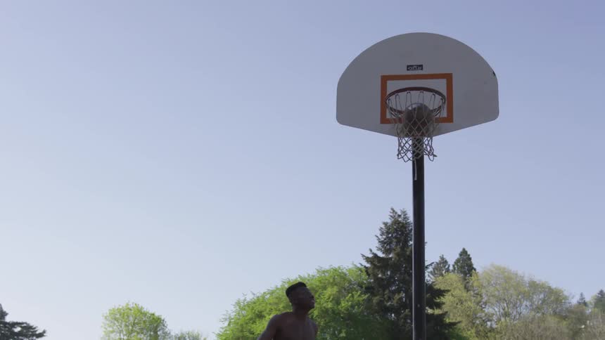 Male dribbling basketball then shooting at net at the park