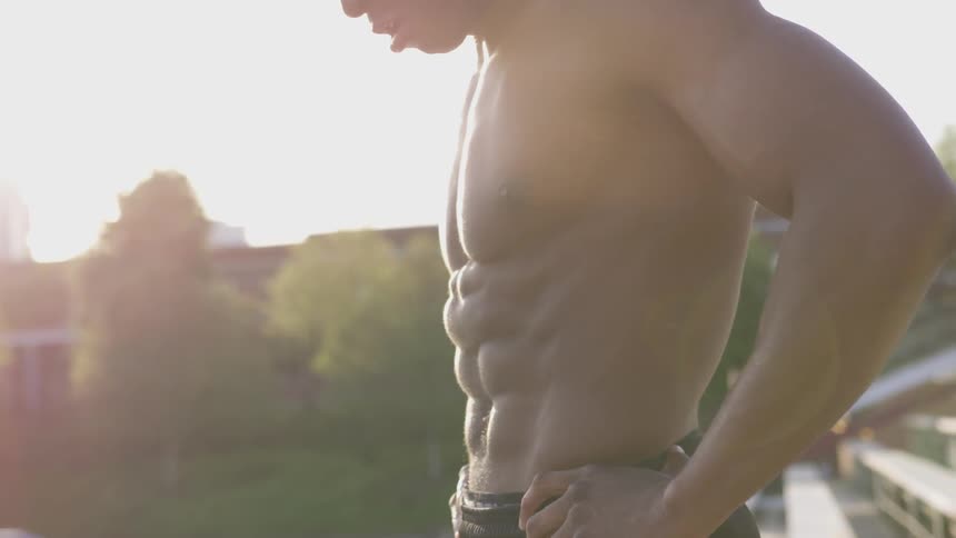 A thickly muscled man standing on the bleachers