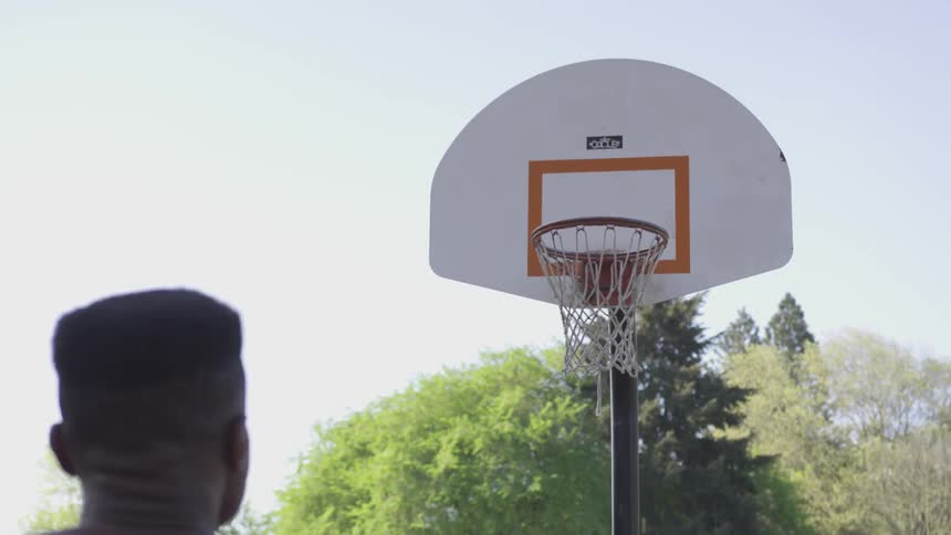 A young man shoots a basketball and makes it in the hoop